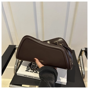 Detail of a chocolate brown wavy faux leather shoulder bag with gold zipper and logo