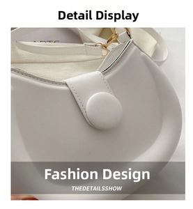 Detailed close-up of white crescent crossbody bag with gold hardware and fine stitching