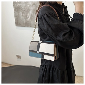 Detail of color-block shoulder bag with leather handle and golden chain strap