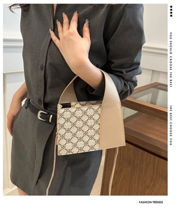 Detailansicht einer beigen Patchwork-Handtasche mit Vintage-Print, von einem Model getragen