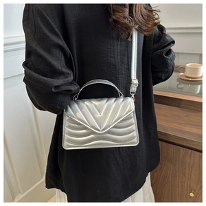 Close-up of silver quilted crossbody bag with gold hardware and V-shaped stitching detail