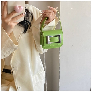 Macro detail of vibrant green mini bag with oversized silver buckle and chain strap