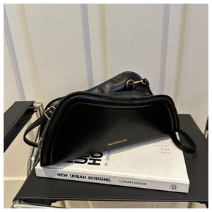 Detail view of black crescent shoulder bag with gold hardware on a book