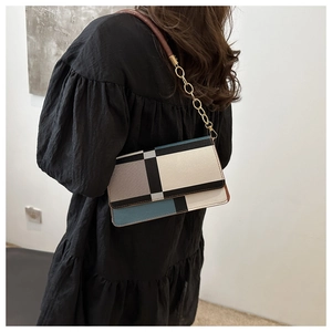 Detail of color-block geometric pattern on textured leather shoulder bag with gold chain