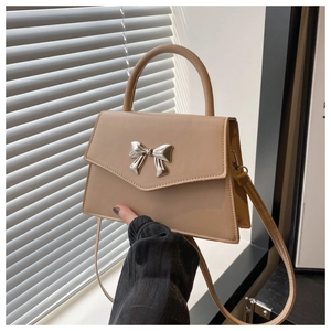 Detailed close-up of a stylish beige handbag with an elegant metal bow ornament