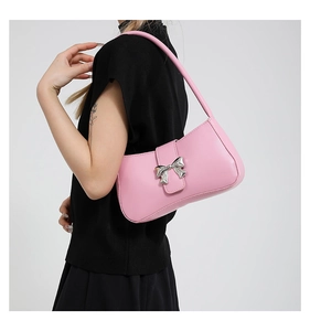 Detail der rosa Schultertasche mit metallischer Silberschleife auf glattem Kunstleder