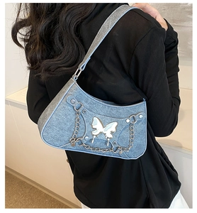 Detalle de bolso denim azul claro brillante con mariposa plateada y cadena metal