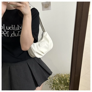 Mirror selfie showing the white pleated crescent underarm bag with smooth faux leather texture