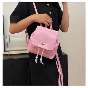 Detail of pink mini backpack with golden metal twist lock and colorful beaded drawstring