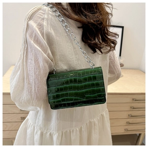 Detailed close-up of dark green faux crocodile skin texture and silver chain on handbag