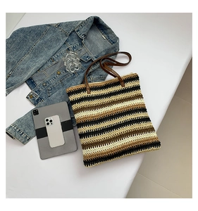 Flat lay of a striped woven tote bag with brown handles and lifestyle accessories