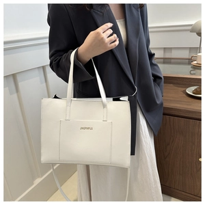 Detailed shot of white tote bag featuring front pocket with gold lettering and dual straps