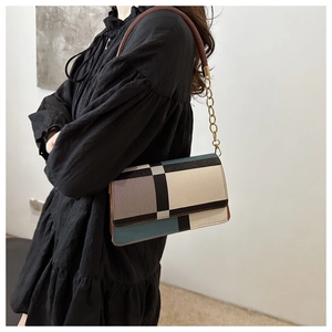 Close-up of color-block geometric patterns on a stylish crossbody bag with gold hardware