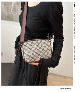 Modèle portant un sac bandoulière vintage à motifs avec bordure en cuir et sangle