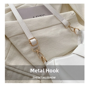 Close-up of white leather crossbody bag with premium light gold metal hardware hooks