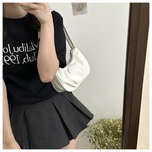 Mirror selfie showing the minimalist white pleated crescent bag worn as an underarm shoulder bag