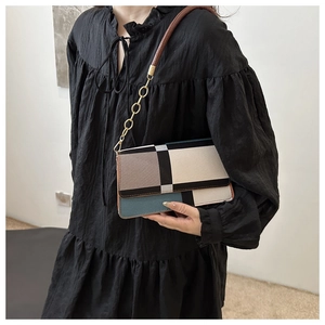 Detail of geometric color-block shoulder bag with gold chain strap and leather texture