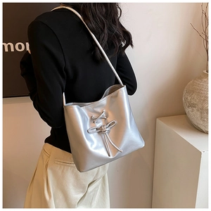 Détail du sac cabas argenté métallisé avec un nœud décoratif et une fine bandoulière