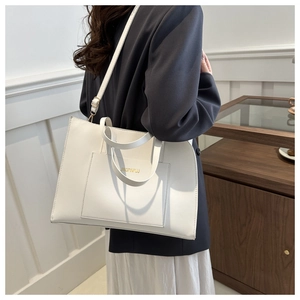 White large capacity leather tote bag with shoulder strap worn by a model in casual style