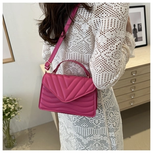 Detail view of fuchsia quilted crossbody bag with adjustable strap and V-pattern stitching