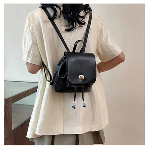 Detail of black mini backpack with flap twist lock and drawstring bead decoration