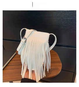 Detail of white lychee leather crossbody bag with long fringes and adjustable strap