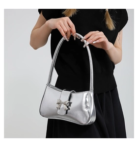 Detail der silbernen Metallic-Achseltasche mit Schleife auf einem schwarzen Oberteil