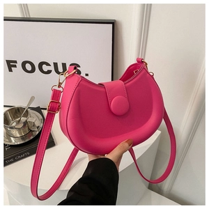 Detail of a magenta half-moon shoulder bag with smooth texture and magnetic buckle closure