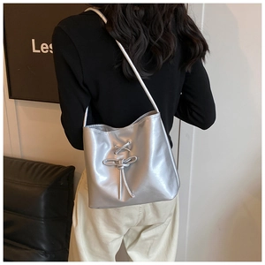 Detail of silver metallic mirror shoulder bag with trendy lace-up ribbon bow decoration