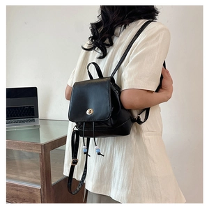 Close-up of black PU leather mini backpack with gold twist lock and bead drawstring