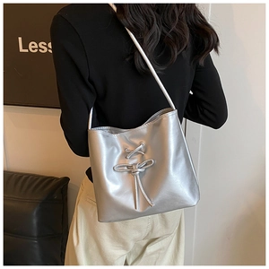 Close-up of metallic silver tote bag with lace-up bow detail and glossy finish