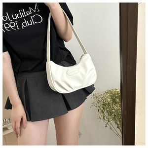White hobo shoulder bag styled as an underarm bag on model in a mirror reflection