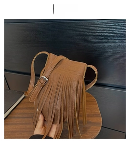 Close-up of brown litchi texture leather bucket bag with long tassels and adjustable strap