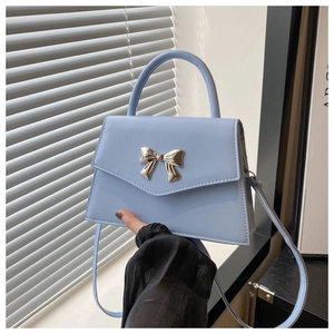 Detail of light blue crossbody bag with silver bow buckle and glossy leather finish