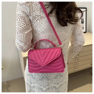 Close-up of fuchsia chevron quilted crossbody bag shown on model in white lace dress
