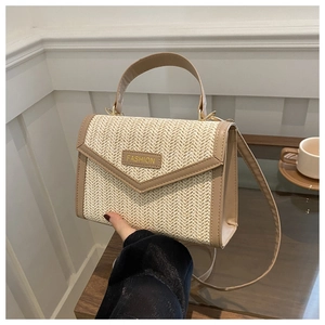 Gros plan d'un sac en paille tressée beige avec finitions en cuir et plaque fashion