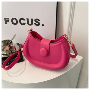 Detail view of fuchsia half-moon shoulder bag with smooth padded texture and gold hardware