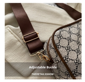 Détail de la boucle dorée ajustable et de la bandoulière marron sur un sac beige