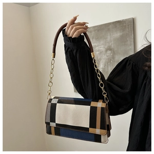 Detail of color-block patchwork shoulder bag with brown handle and gold chain