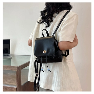 Detail of black leather mini backpack featuring golden twist lock and beaded drawstring