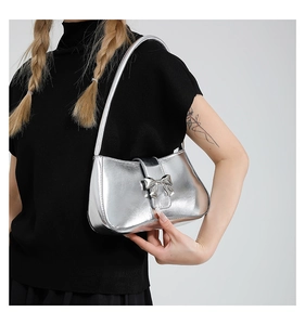 Silberne Metallic-Schultertasche mit Schleife an einem Modell im modernen Stil