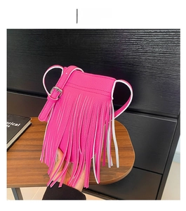 Close-up of litchi leather crossbody phone bag with fringe and silver buckle in rose red