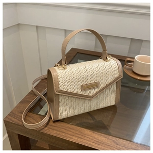 Détail du sac en paille tressée avec plaque dorée FASHION et poignée en cuir