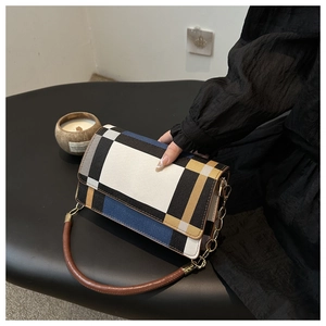 Detail view of contrast color block handbag with gold chain strap and brown handle