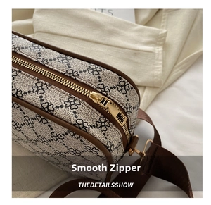 Détail de la fermeture éclair fluide et du passepoil en cuir brun sur le sac en toile vintage