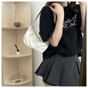 Detail of white pleated moon bag showing soft faux leather texture and embossed logo