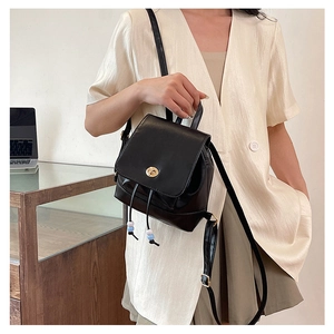Detail of black leather mini backpack featuring gold twist lock and beaded drawstring