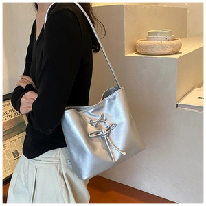 Detail of silver metallic shoulder bag with lace-up bow and modern slouchy design