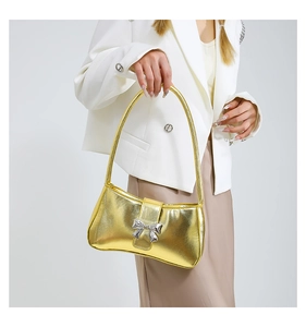 Nahaufnahme der goldenen Hobo-Tasche mit silberner Schleife am Outfit eines Models