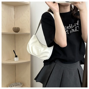 Detail of white pleated underarm bag showing the oval embossed logo and leather texture